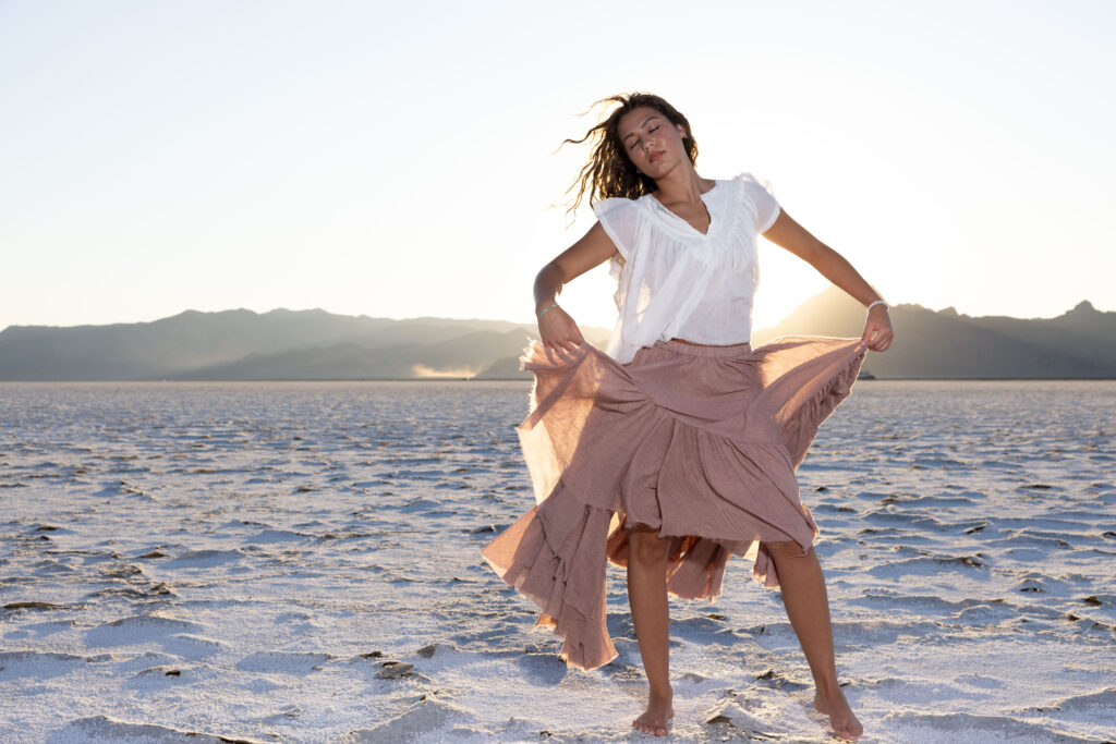 woman holding skirt in front of sunset at the Bonneville Salt Flats.